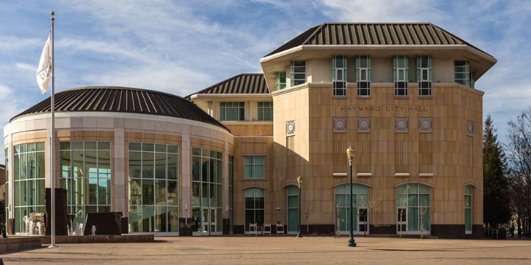 Photo of Hayward City Hall, a large tan building with a circular building with windows.