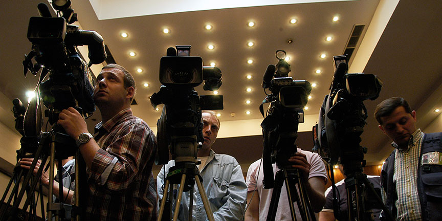 A group of cameramen standing in a row with their cameras