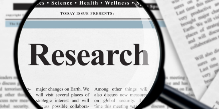 A newspaper with a magnify glass focused on the word research