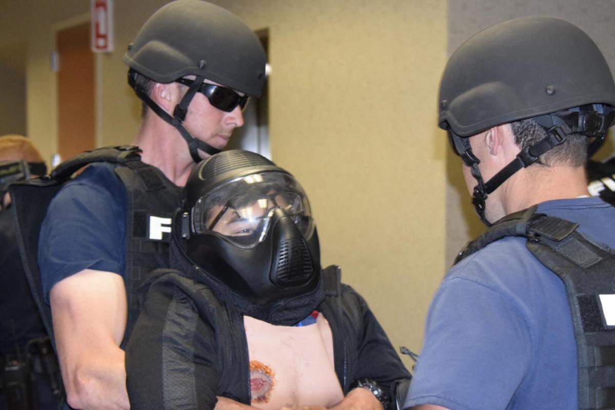 Police officers and fire fighters in tactical gear carry a fake trauma victim