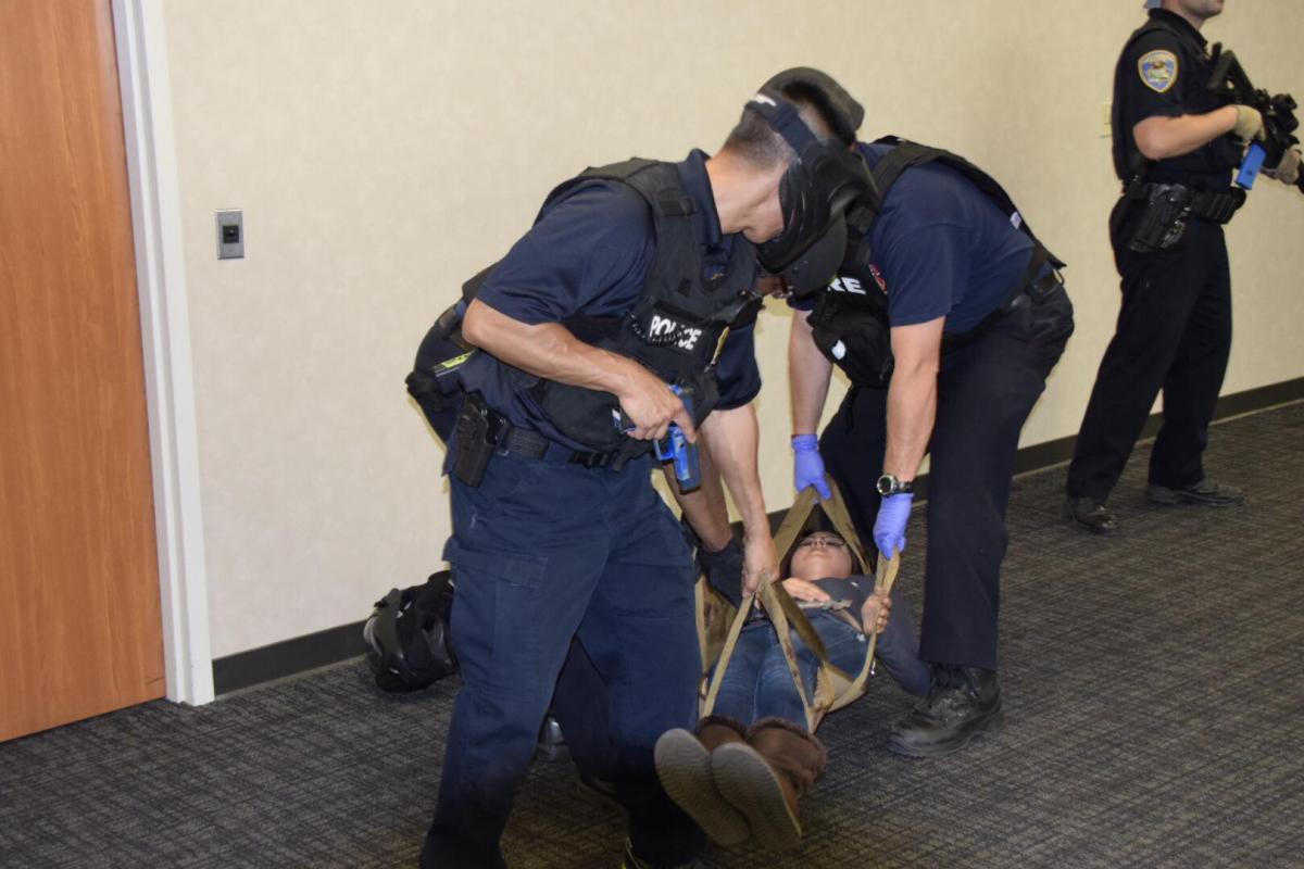 Fire Fighters in tactical gear carry a fake victim out in a hall