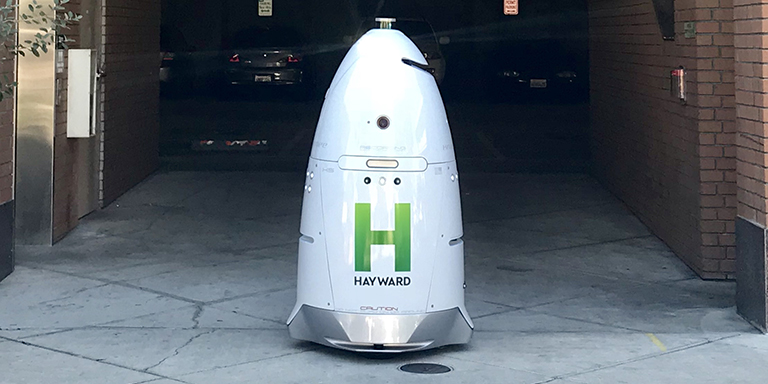 White Knightscope robot with green Hayward H on it, outside of the Watkins Street garage