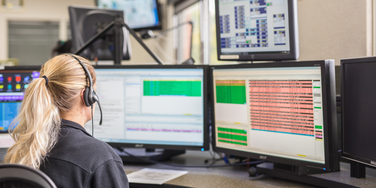 A woman sitting at a dispatch center computer taking calls 