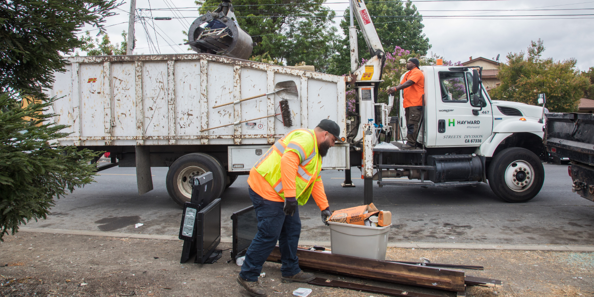 Two Maintenance Service workers cleaning up an illegal dumping site