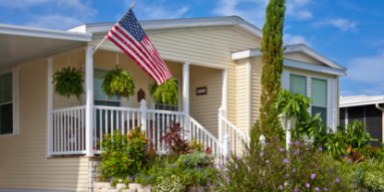 A mobile home with an American flag on the porch