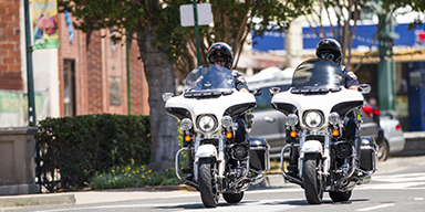 Two police officers riding motorcycles down the street