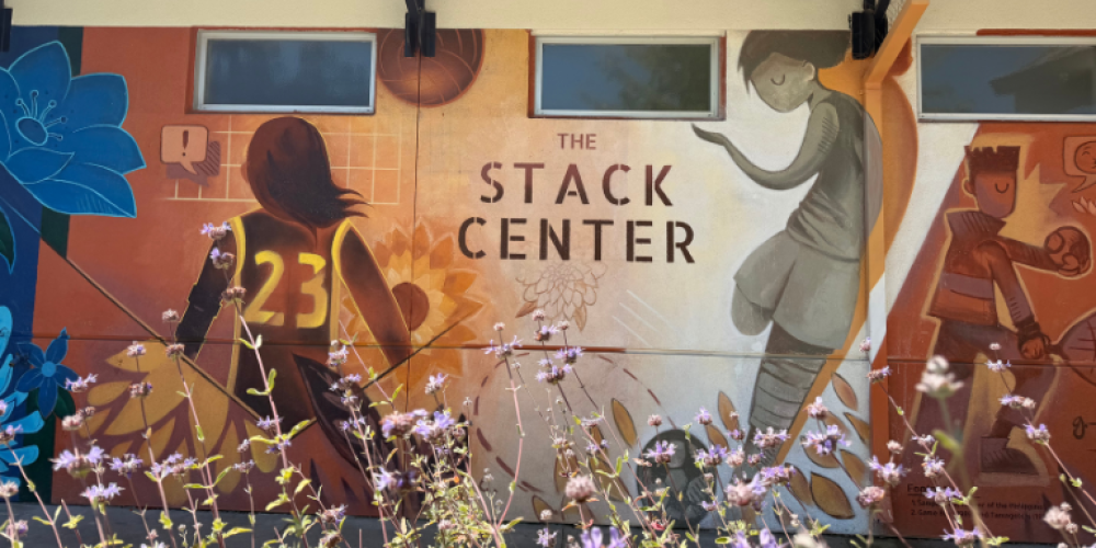 Mural of children playing basketball next to the text, "The Stack Center"