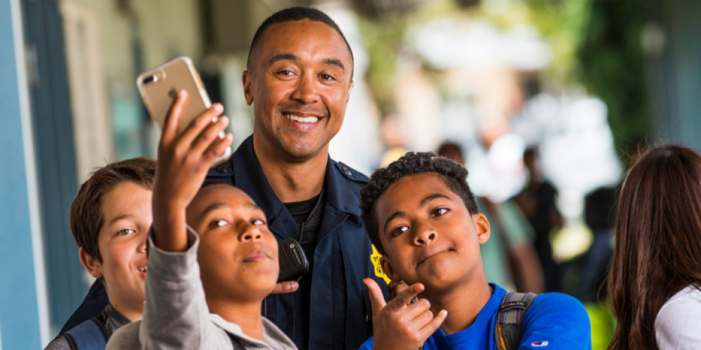 A member of the police department taking photos with three young students
