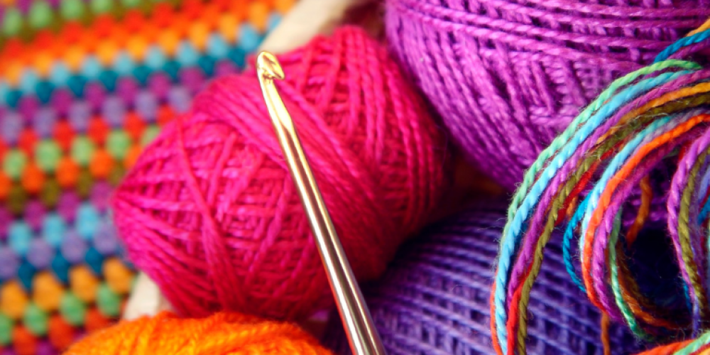 Colorful yarn and a gold crochet hook