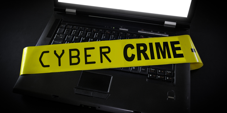 Yellow crime tape with the text "Cyber Crime" cover a laptop. 