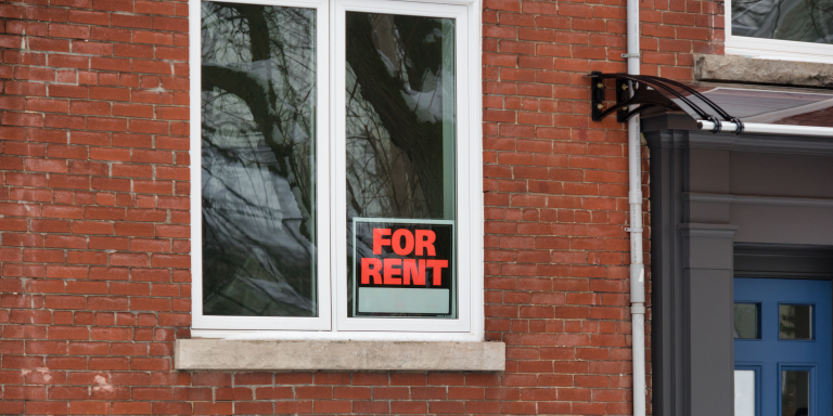 An apartment with a for rent sign in the window