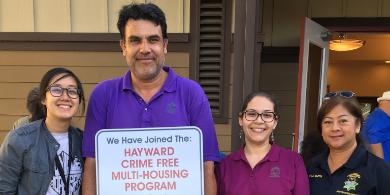 people standing with a crime free multi housing sign