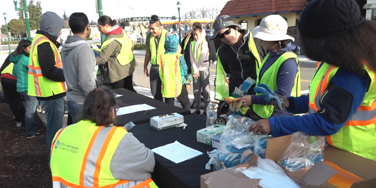 Men and women in yellow Keep Hayward Clean and Green vests getting ready for a cleanup event