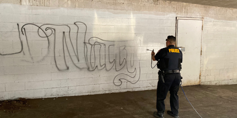 a police officer painting over graffiti
