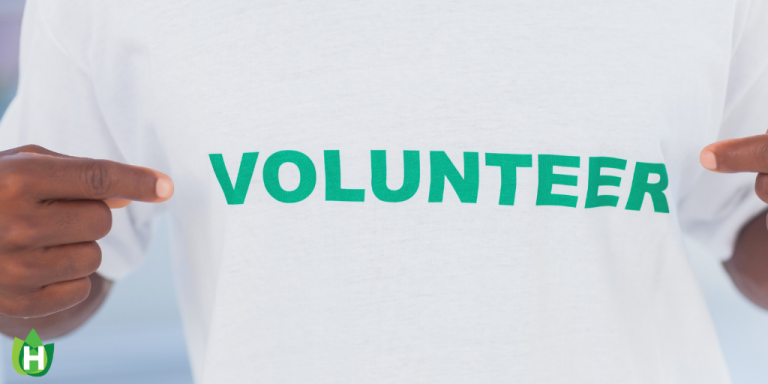 A person wearing a white shirt with the word "Volunteer" in green across their chest