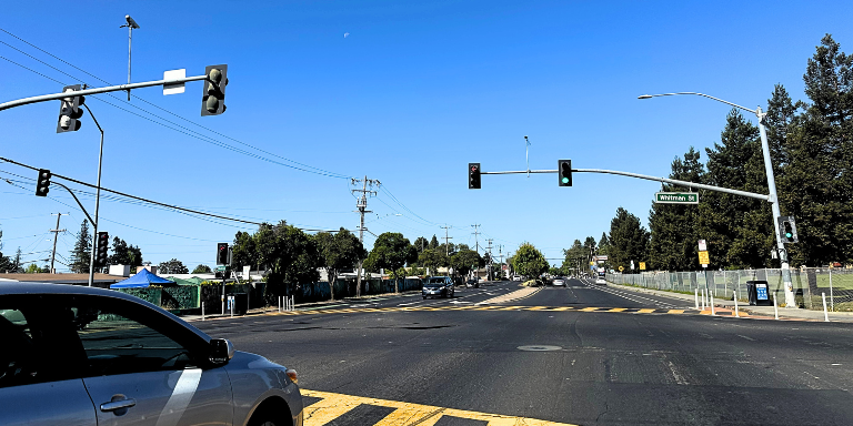 Photo of a car at at traffic signal on Tennnyson Road and Whitman Street. 