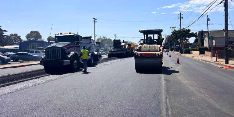Photo of a truck and a machine roller paving a street in Hayward.